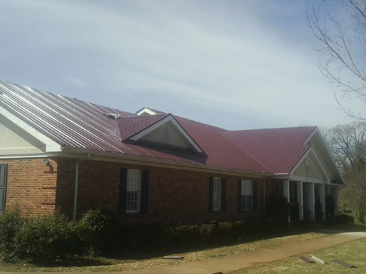 Red metal roof with gabled entries on a long brick building in Newsoms