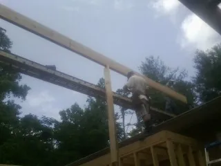 Carpenter setting a ridge beam over a new addition frame — Ice Dam Removal by Roofing Brothers in Newsoms