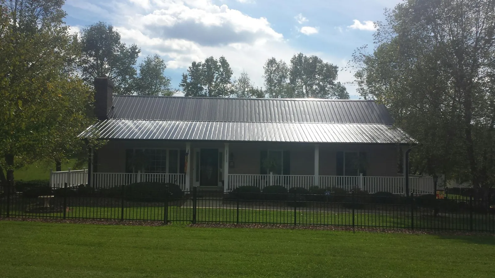 Gray metal roof on a brick ranch with a full width front porch — Gutter Guard Installation work by our crew in Newsoms