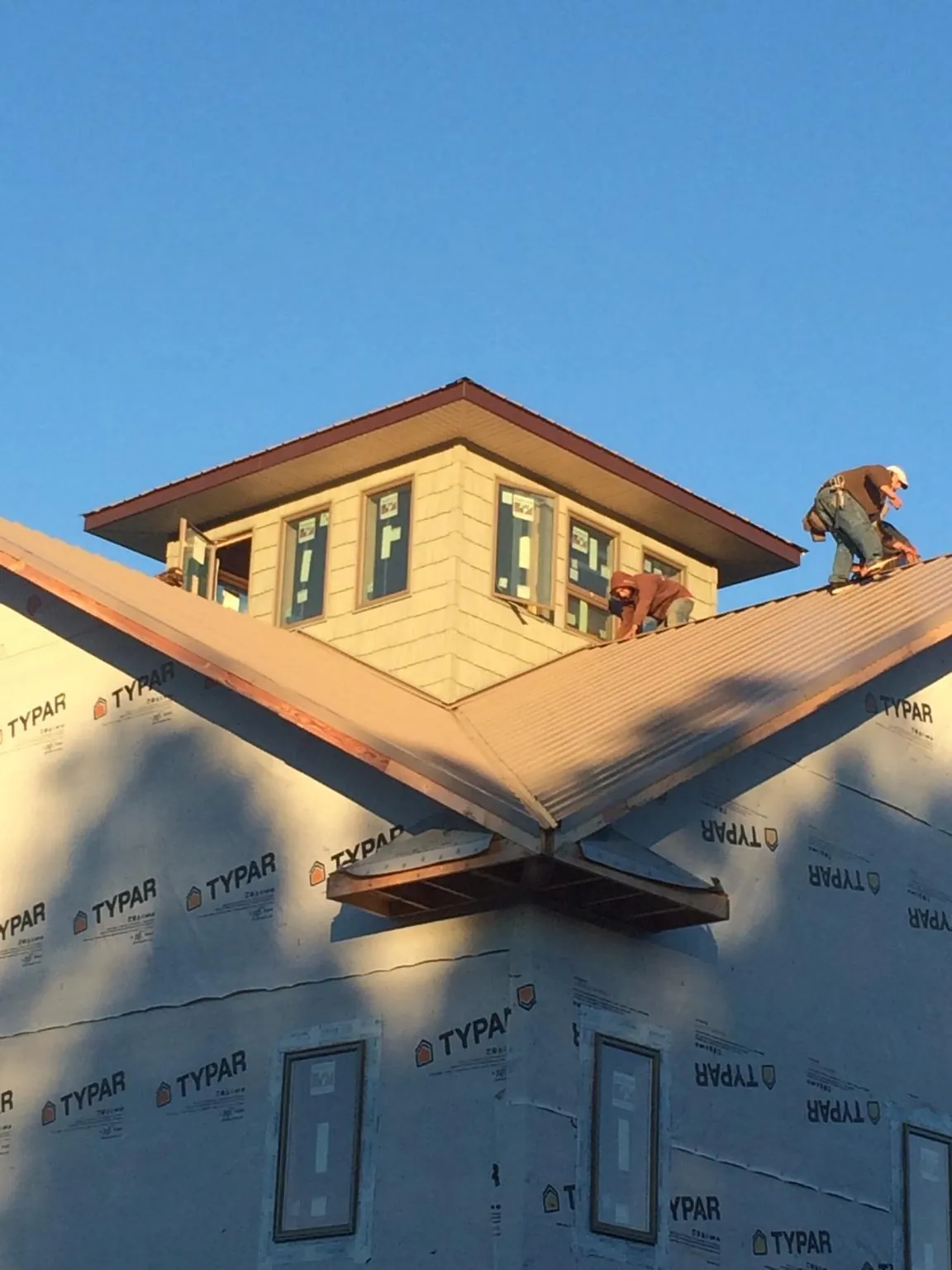 Roofers working around a rooftop cupola on a new metal roof at sunset — Roof Waterproofing in Newsoms by Roofing Brothers